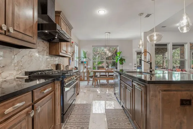 a kitchen with stainless steel appliances granite countertop a sink a stove and a refrigerator
