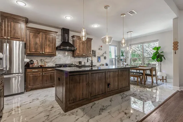 a kitchen with kitchen island granite countertop a stove a sink a oven a dining table and chairs with wooden floor