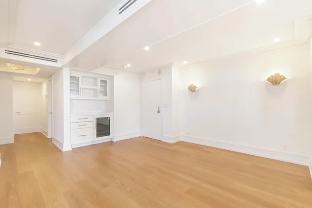 a view of an empty room with wooden floor and windows