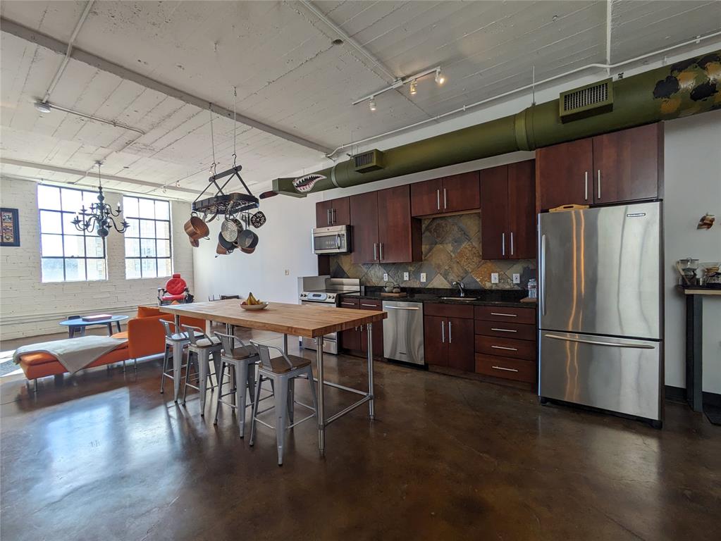 1122 Jackson Street, Unit 301 Dallas, TX 75202 - Photo 7 of 23 a kitchen with stainless steel appliances granite countertop a refrigerator a stove a sink a dining table and chairs with wooden floor