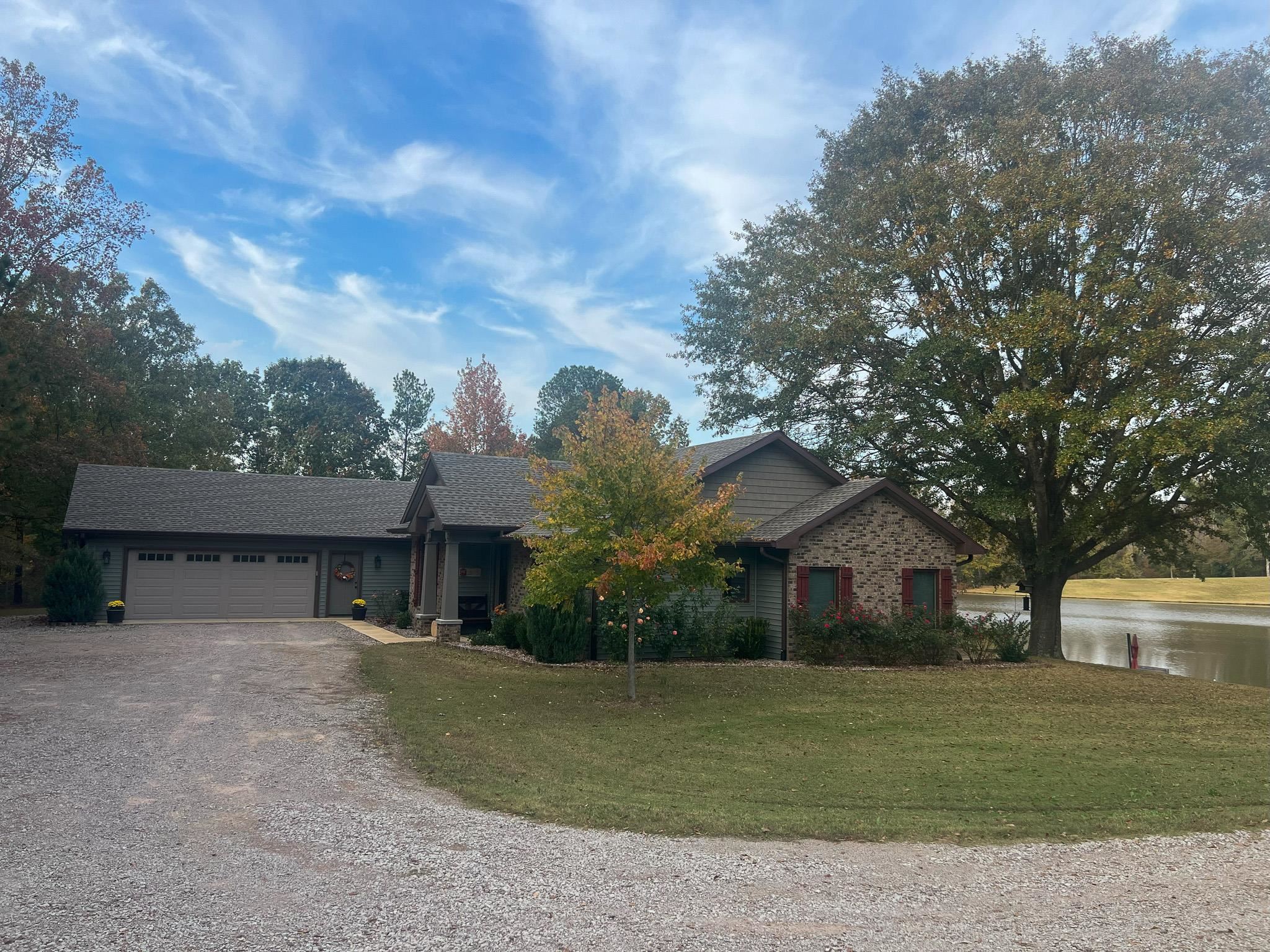 Ranch-style house with a front yard, a water view, and a garage