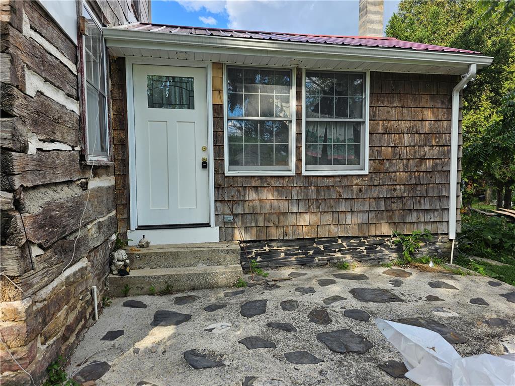9128 Slateville Road Kempton, PA 19529 - Photo 4 of 13 A charming log and shingle-sided home features a white entry door and stone foundation details.