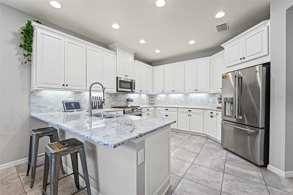 8903 Arabella Lane Seminole, FL 33777 - Photo 7 of 47 a kitchen with stainless steel appliances granite countertop a sink a stove a refrigerator and cabinets