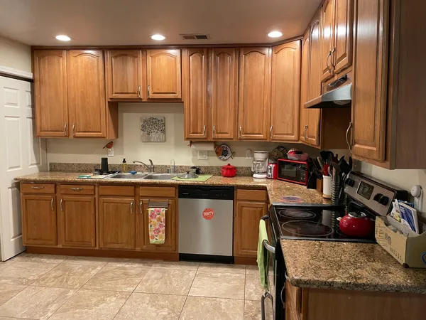 a kitchen with kitchen island granite countertop wooden cabinets and a sink