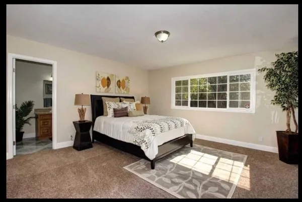 a bed sitting in a bedroom next to a window and a chair