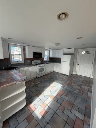 a large hall with stainless steel appliances granite countertop a stove and a sink