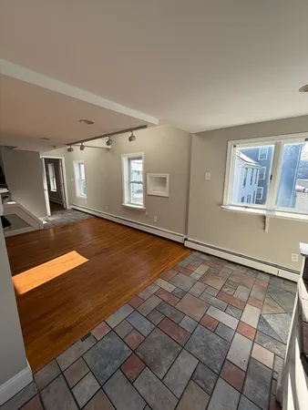 a view of an empty room with window and wooden floor