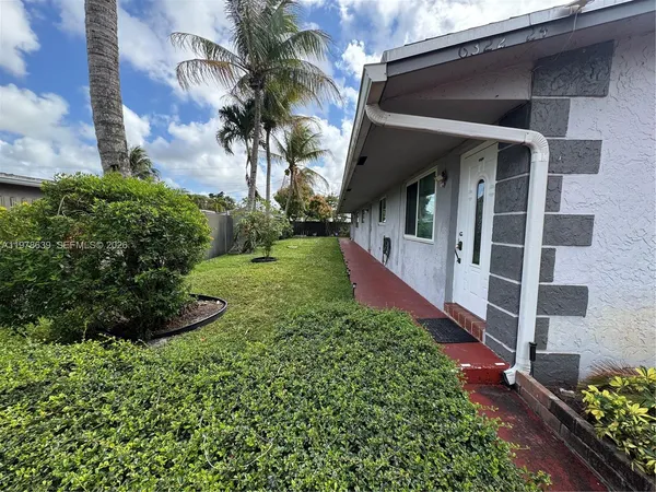 a view of a house with a small yard plants and large tree