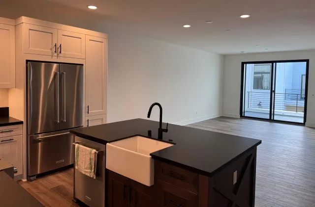 a kitchen with a sink a refrigerator and wooden floor