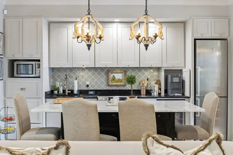 a kitchen with stainless steel appliances granite countertop a dining table chairs stove refrigerator and microwave