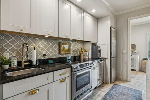a kitchen with granite countertop a sink a stove and refrigerator