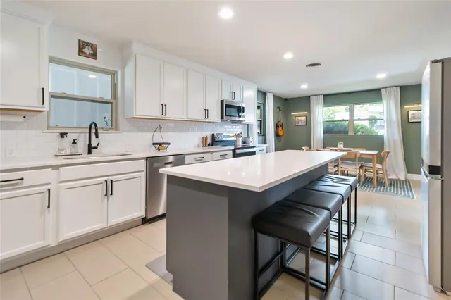 a kitchen with a sink chairs and white cabinets