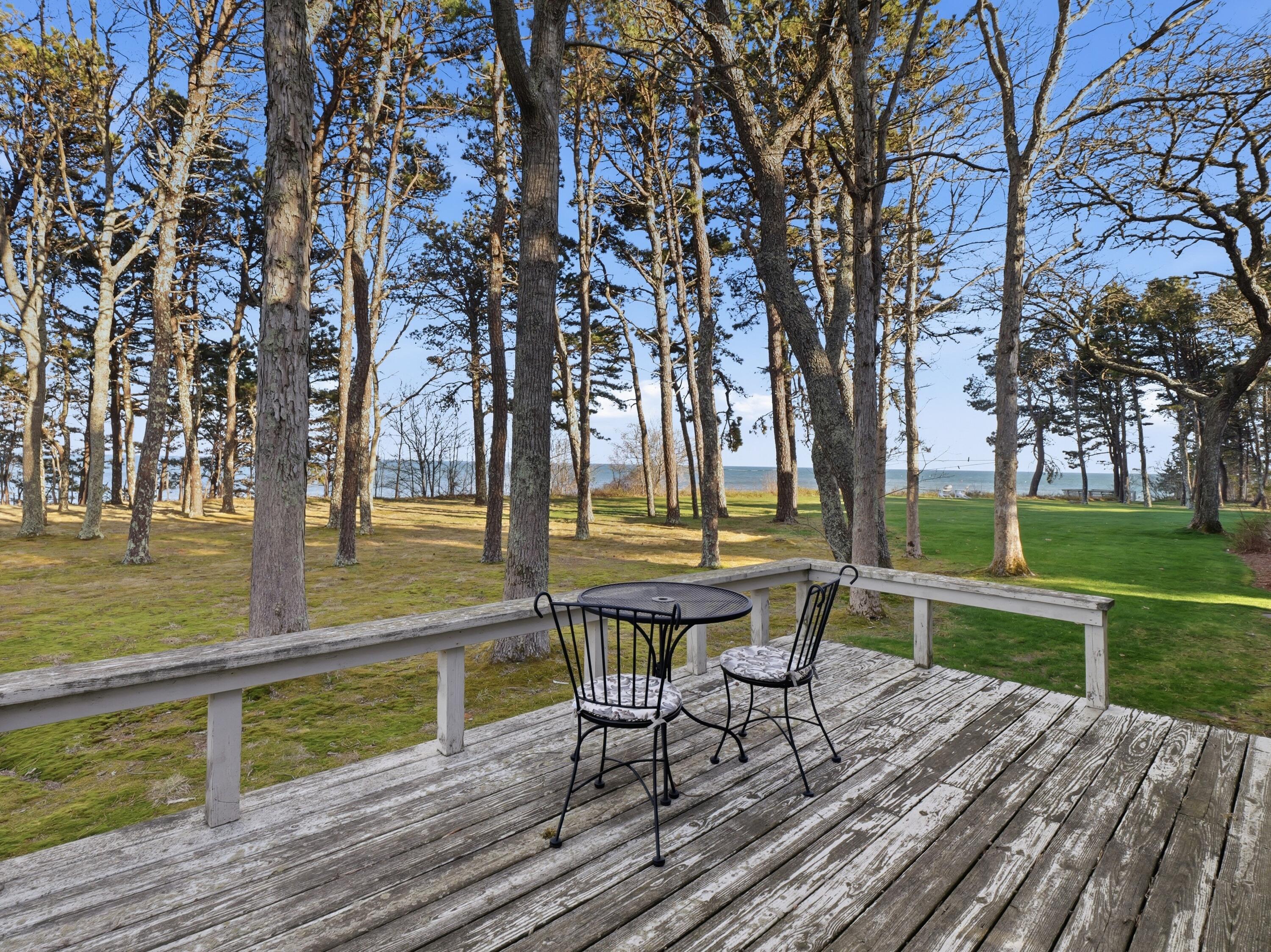 190 Vineyard Road Cotuit, MA 02635 - Photo 31 of 41 a view of a lake with table and chairs and wooden fence