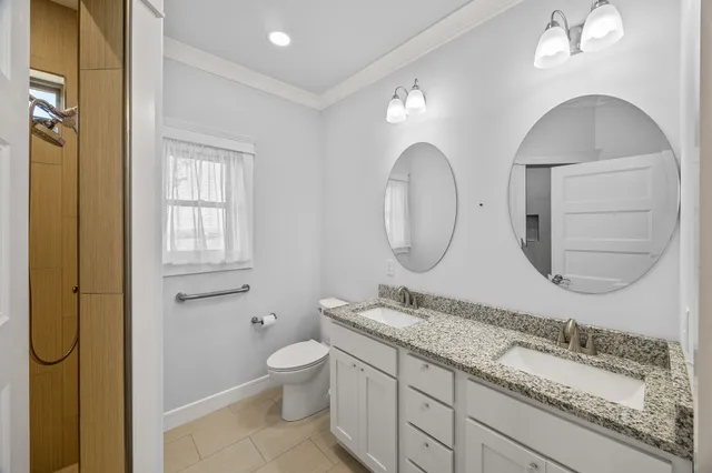 a bathroom with a granite countertop toilet a sink and a mirror