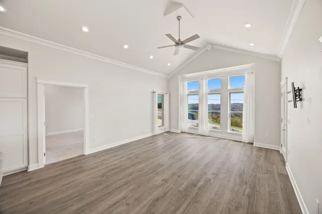 an empty room with wooden floor fan and windows
