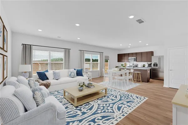 a living room with furniture a flat screen tv and kitchen view