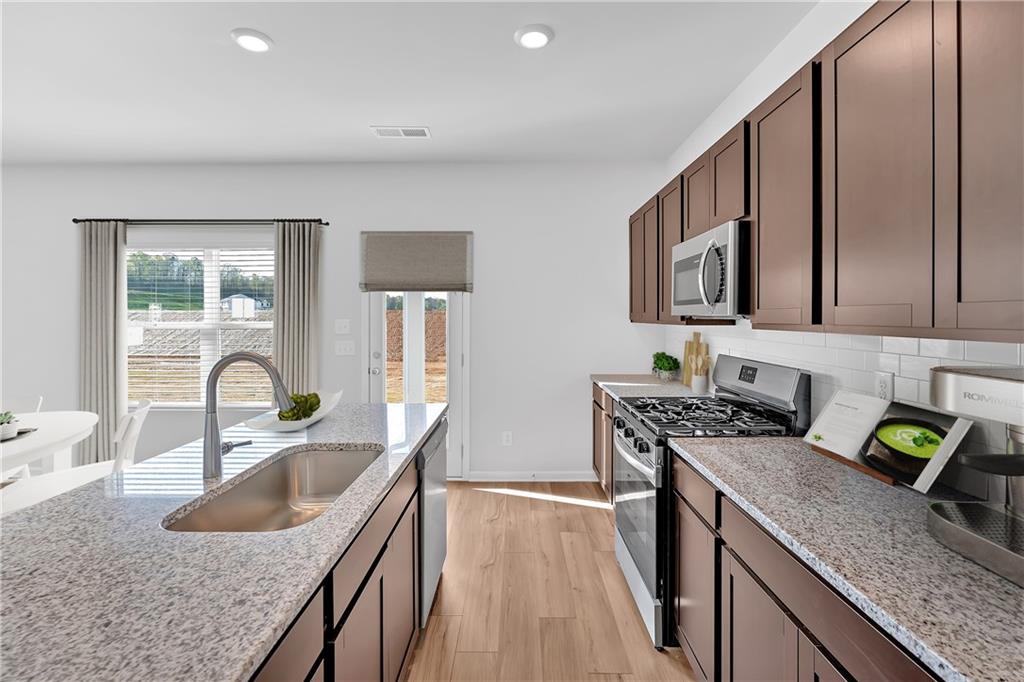 107 Lavender Circle Calhoun, GA 30701 - Photo 10 of 23 a kitchen with granite countertop a sink a stove and wooden cabinets