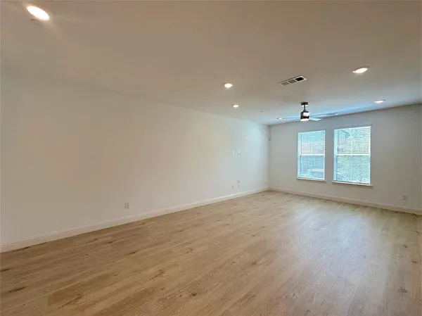 an empty room with wooden floor and windows