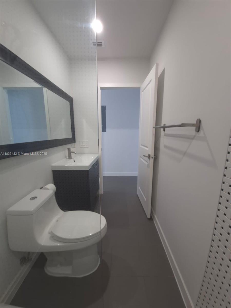 1211 Euclid Avenue, Unit 11 Miami Beach, FL 33139 - Photo 18 of 19 a white toilet sitting next to a bathroom sink and a mirror