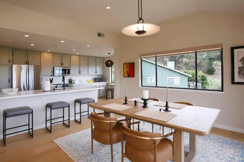 a kitchen with a dining table chairs stainless steel appliances and cabinets