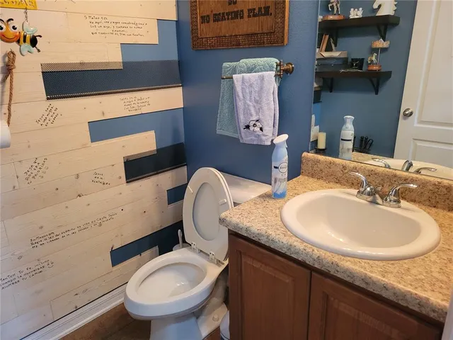 a bathroom with a granite countertop toilet sink and mirror