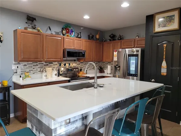 a kitchen with a refrigerator a stove a sink a dining table and chairs