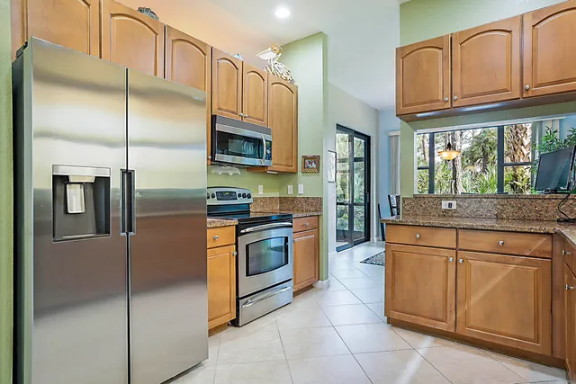a kitchen with stainless steel appliances granite countertop a refrigerator a stove and a sink with cabinets