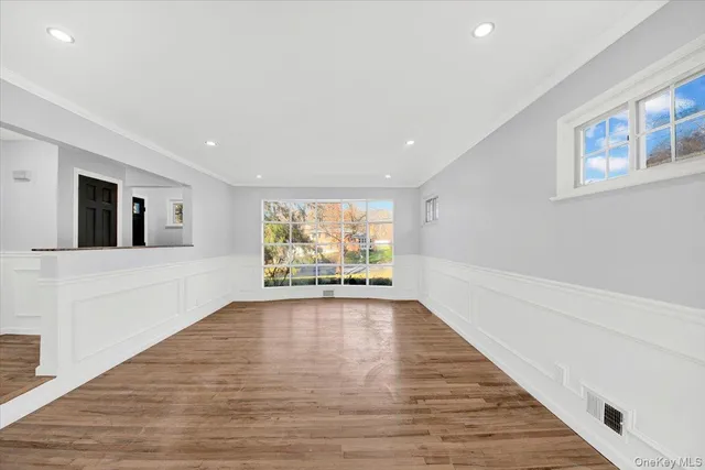 a view of an empty room with window and wooden floor