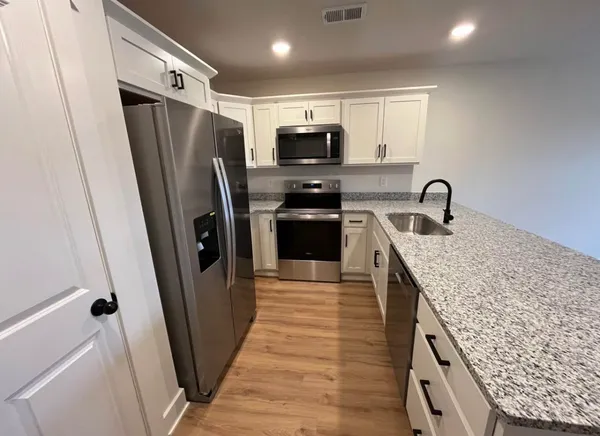 a kitchen with stainless steel appliances granite countertop a refrigerator a sink a stove and cabinets