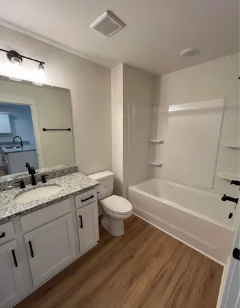 a bathroom with a granite countertop sink toilet a large mirror a bathtub and shower