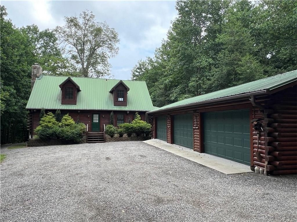 846 Twiggs Ferry Road Hartfield, VA 23071 - Photo 3 of 28 Cabin featuring log siding, a metal roof, a chimney, an outdoor structure, and a detached garage