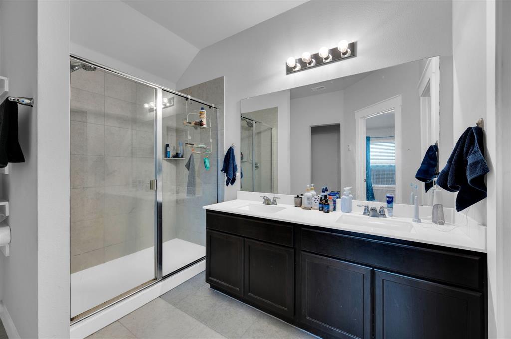 2609 Centurion Road Glenn Heights, TX 75154 - Photo 17 of 29 Bathroom featuring double vanity, lofted ceiling, a shower stall, and light tile patterned flooring