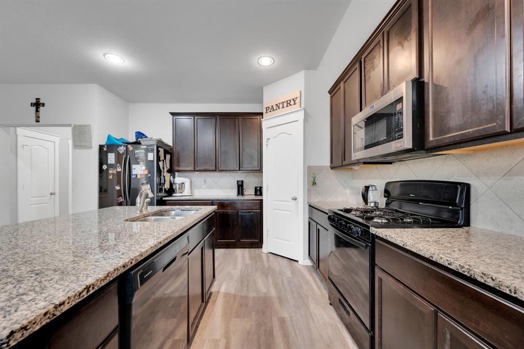 2609 Centurion Road Glenn Heights, TX 75154 - Photo 8 of 29 Kitchen featuring black range with gas stovetop, dark wood finish cabinetry, dishwasher, stainless steel microwave, and light wood-type flooring