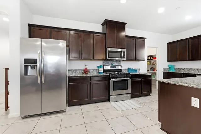 a kitchen with stainless steel appliances granite countertop a refrigerator and a stove top oven