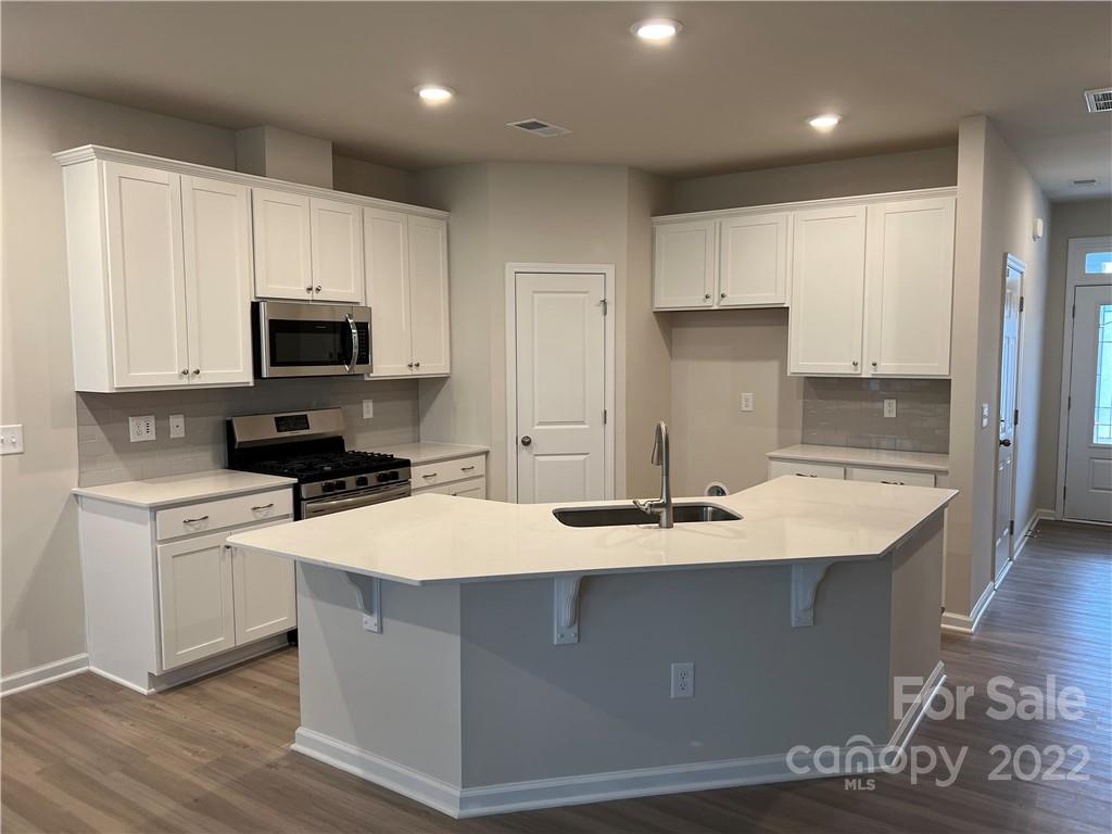 904 Pk Bnd Trail, Unit 71 Tega Cay, SC 29708 - Photo 7 of 14 a large kitchen with stainless steel appliances kitchen island granite countertop a stove a sink a refrigerator and white cabinets