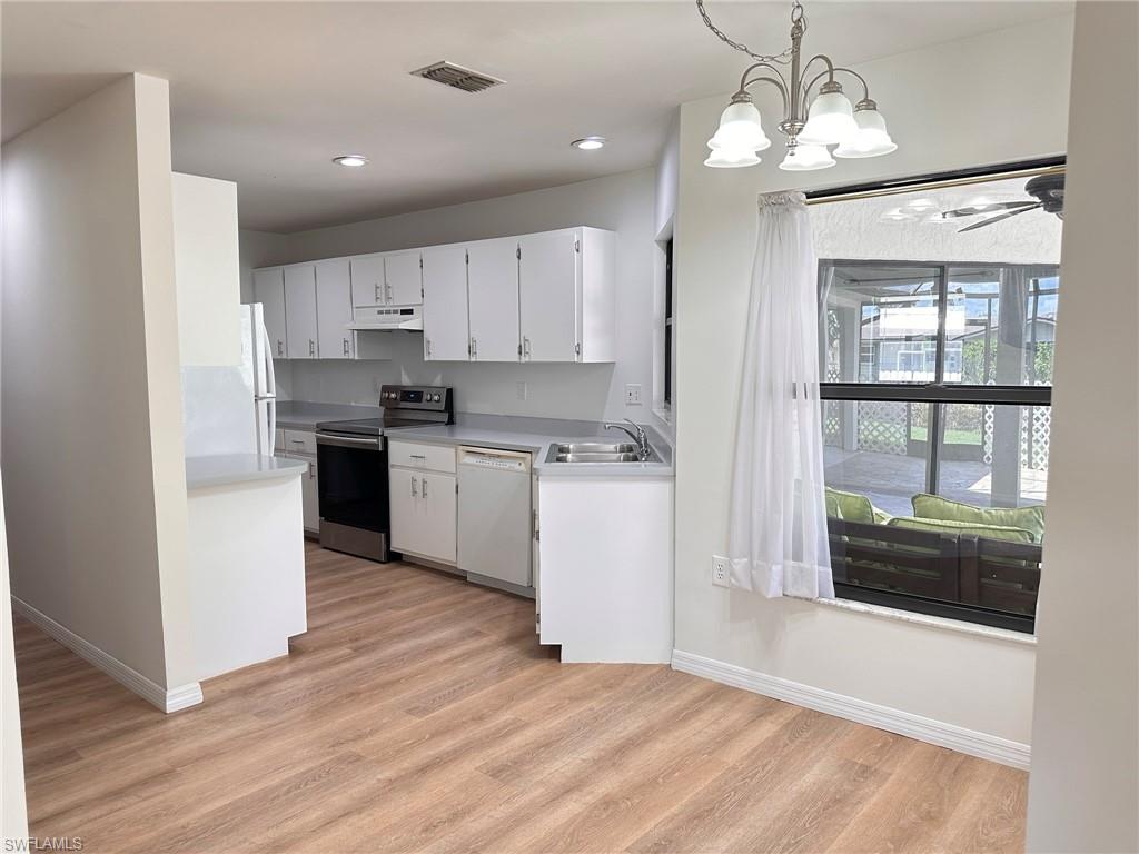 18475 Evergreen Road Fort Myers, FL 33967 - Photo 4 of 30 a kitchen with stainless steel appliances granite countertop a refrigerator a sink dishwasher a stove and white cabinets with wooden floor