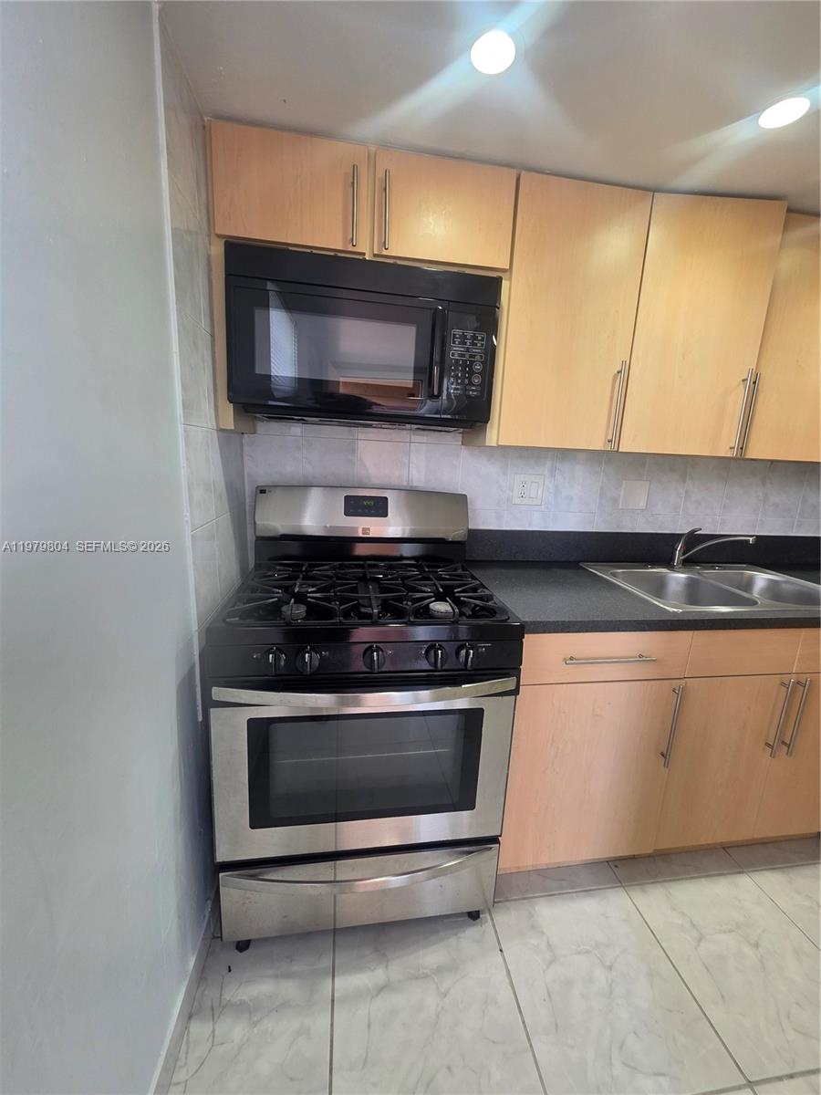 8101 Southwest 73rd Avenue, Unit 17 Miami, FL 33143 - Photo 52 of 66 a kitchen with granite countertop a stove and a microwave