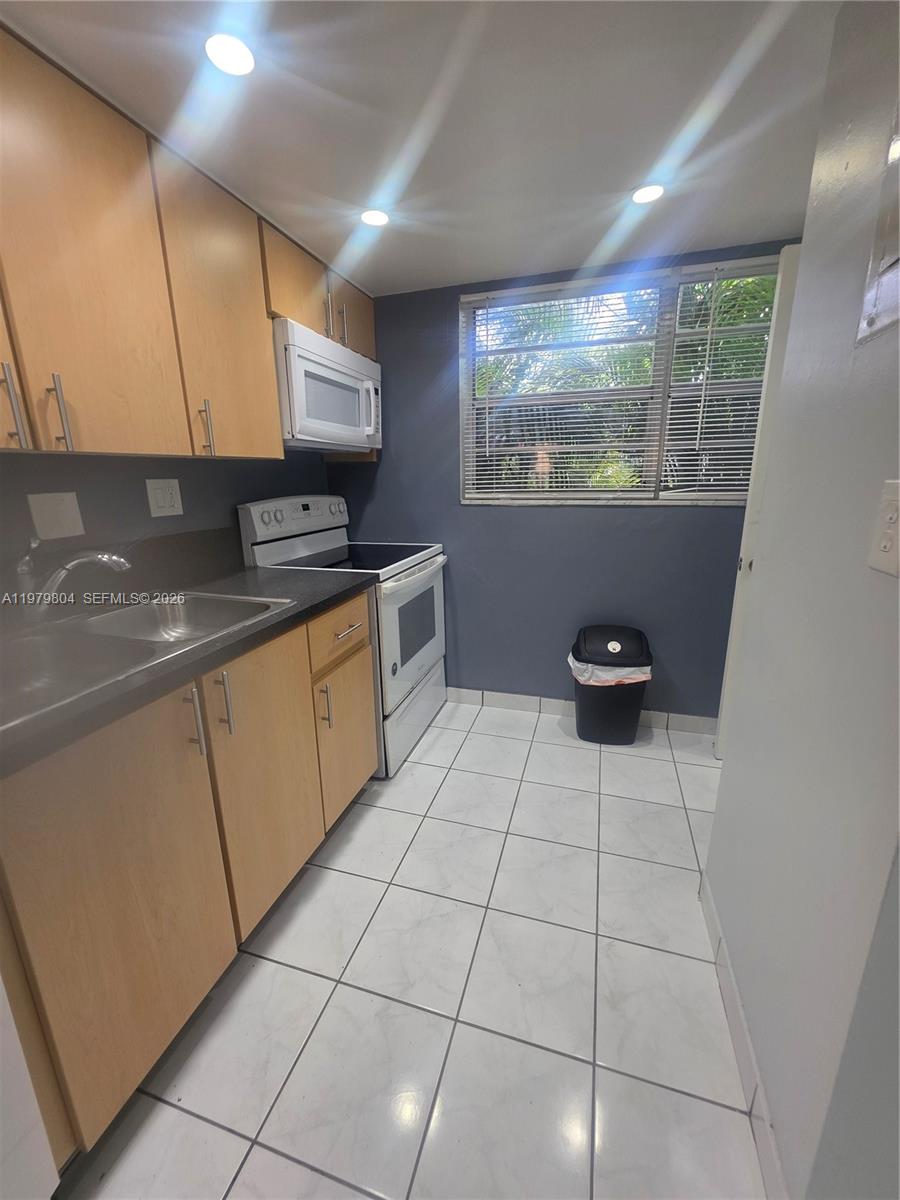 8101 Southwest 73rd Avenue, Unit 17 Miami, FL 33143 - Photo 65 of 66 a kitchen with stainless steel appliances a sink stove and cabinets