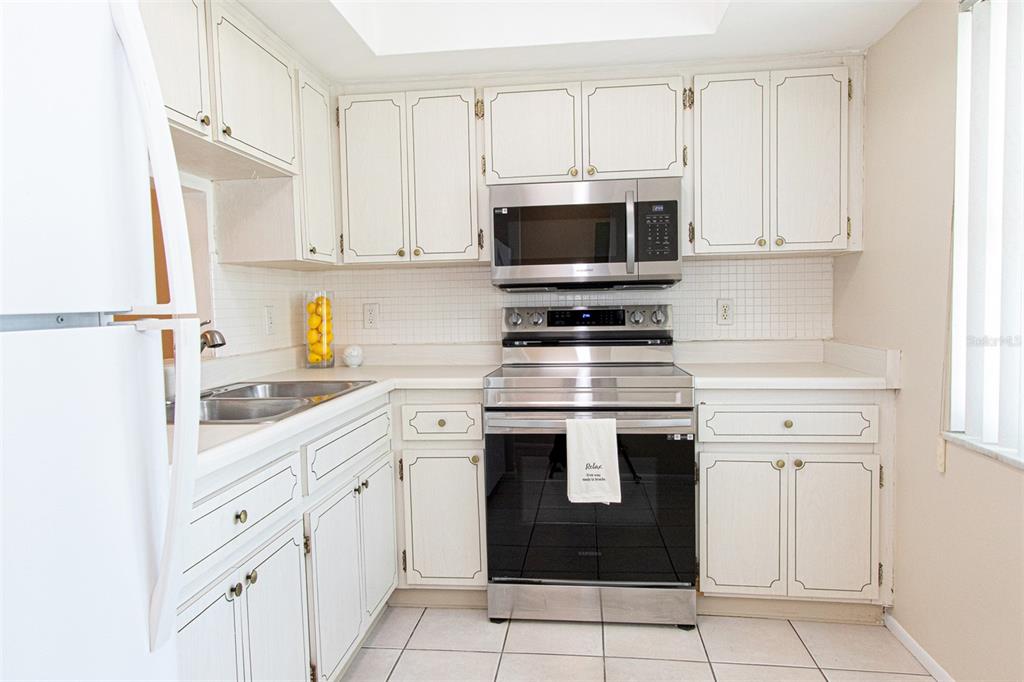 1433 South Belcher Road, Unit F11 Clearwater, FL 33764 - Photo 8 of 21 a kitchen with white cabinets and white appliances