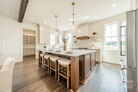 a kitchen with stainless steel appliances granite countertop a stove a sink a refrigerator and a dining table with wooden floor