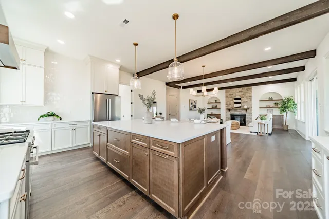 a large white kitchen with a stove a sink a refrigerator and white cabinets with wooden floor