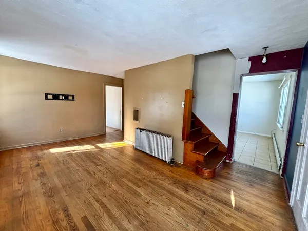 a view of an empty room with wooden floor and stairs