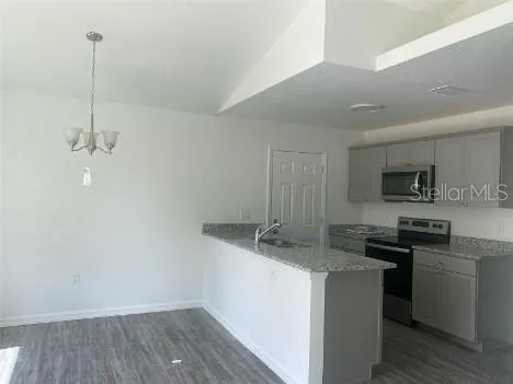 a kitchen with stainless steel appliances granite countertop a sink a stove and a wooden floor