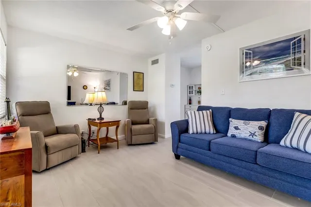a living room with furniture a ceiling fan and a lamp