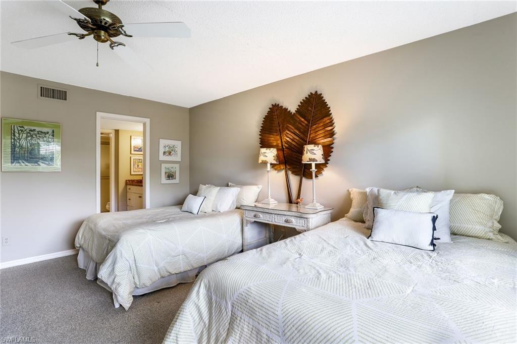 4155 Crayton Road, Unit 108 Naples, FL 34103 - Photo 20 of 32 a bedroom with two beds and a chandelier
