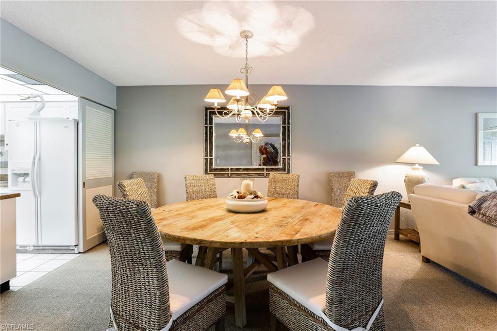4155 Crayton Road, Unit 108 Naples, FL 34103 - Photo 10 of 32 a dining room with furniture a chandelier and window