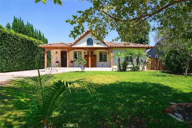 a view of a house with a big yard patio and large tree