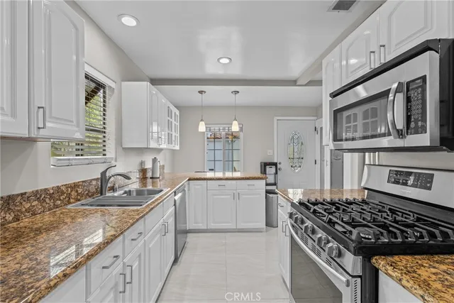 a kitchen with granite countertop a sink stove and cabinets