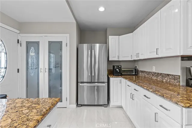 a kitchen with granite countertop a refrigerator sink and cabinets
