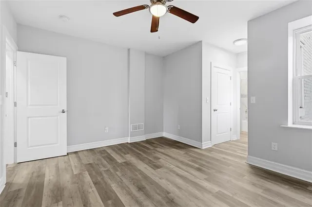 an empty room with wooden floor chandelier fan and windows
